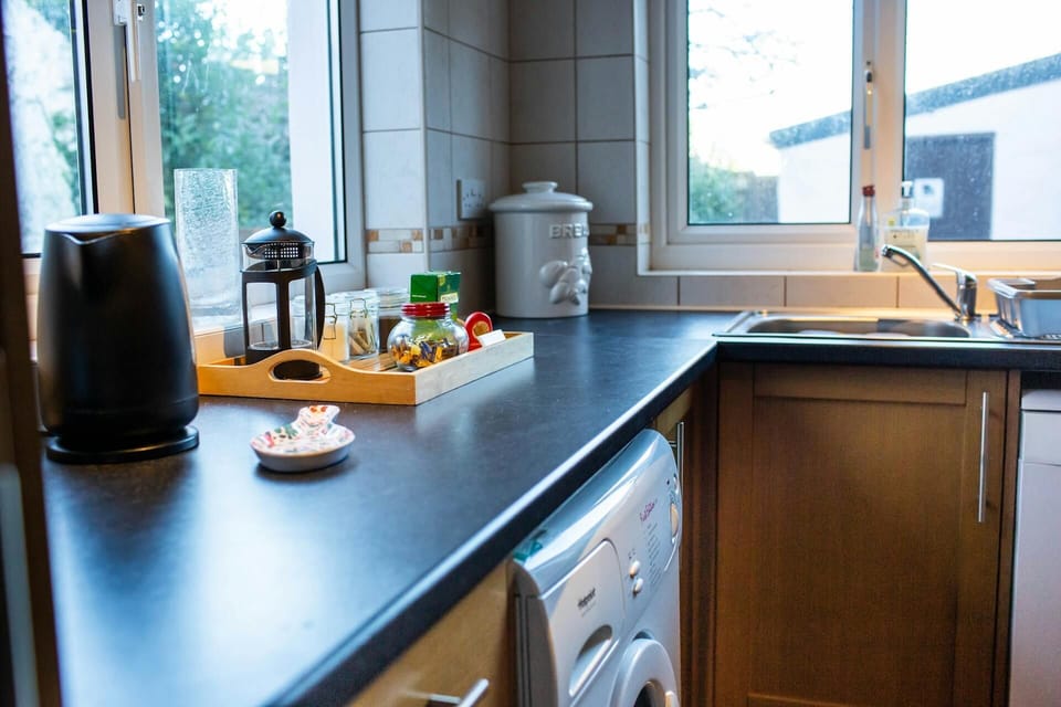 Dark grey worktops. Kettle and tray with tea, coffee and a cafeteria