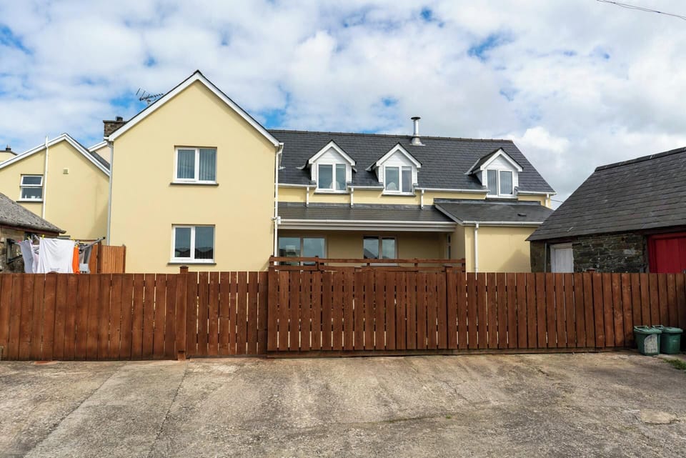 Cnwc Y Boidy. Brown wooden fence with front of cottage behind