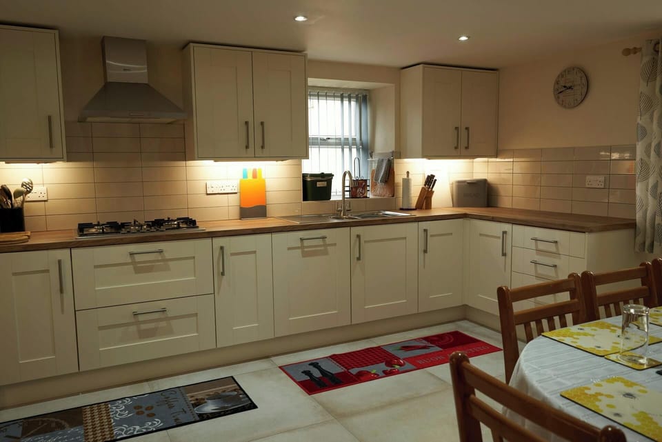 Kitchen cabinets, under cabinet lighting, hob, sink, dining table and chairs