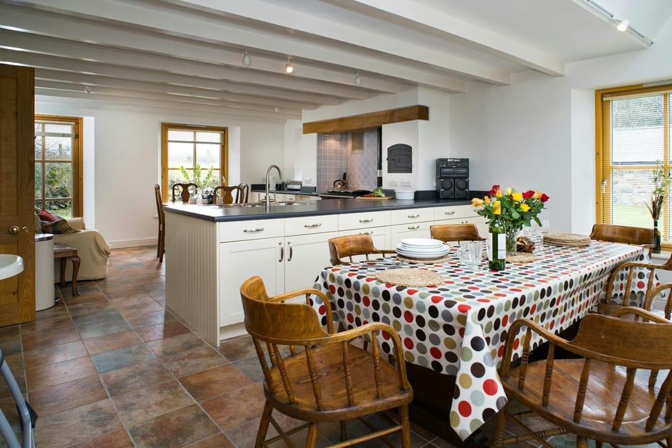 Dining kitchen with large table and six chairs. Tiled floor and 3 windows