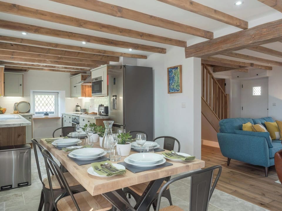 Dining table laid for lunch, sofas and kitchen in the background
