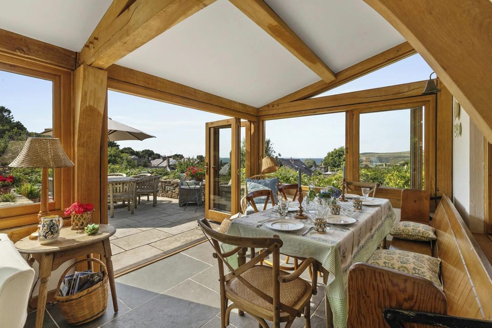 Interior dining area with tableware and chairs, opening onto outdoor seating