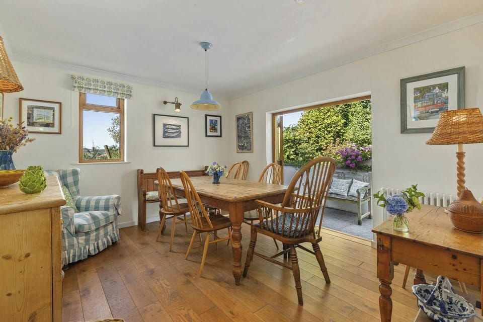 Bright dining room with wooden table and chairs, open doorway to garden