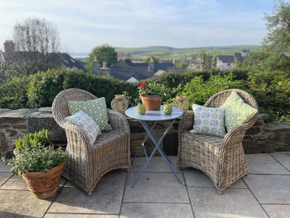 Two wicker chairs and bistro table with distant sea views