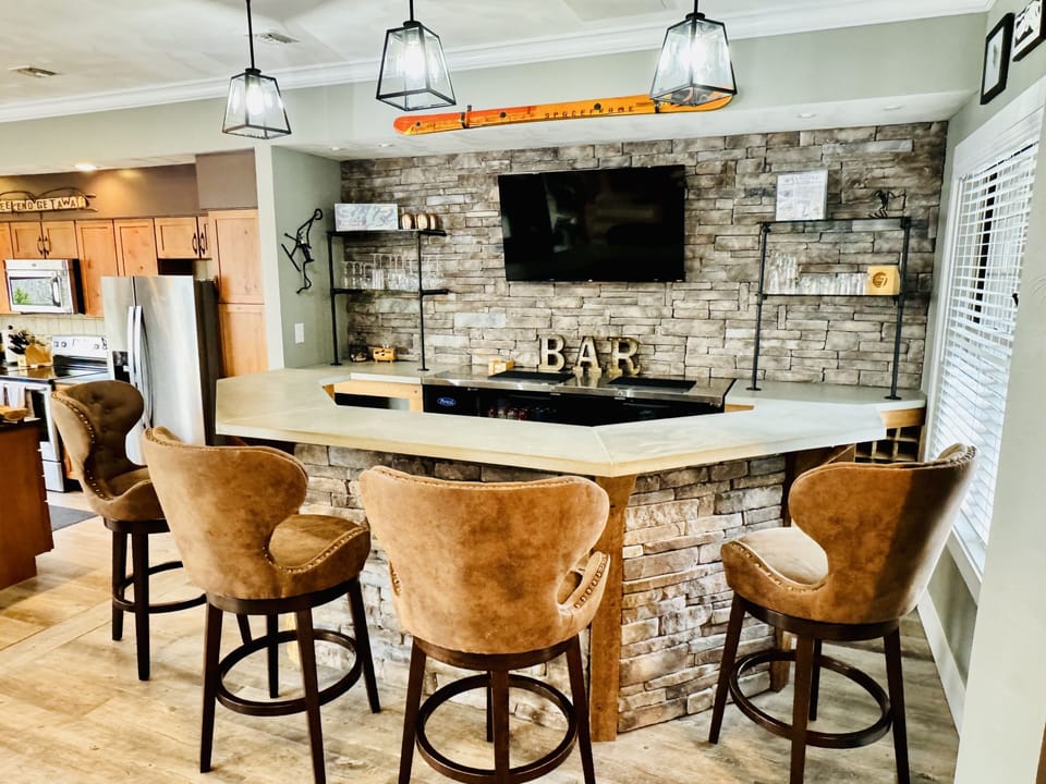 The bar is equipped with glassware and opens to the kitchen/living area