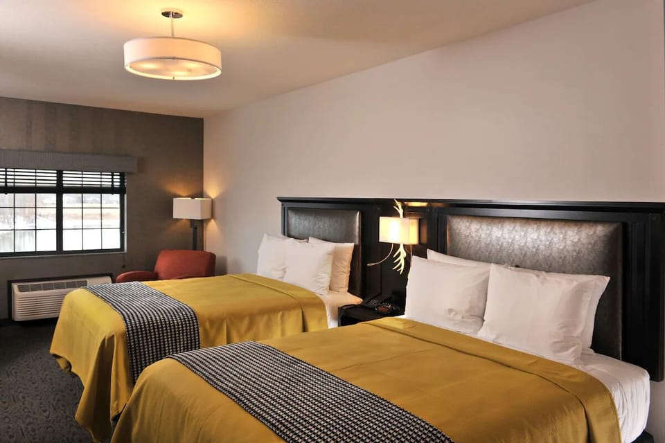 Unwind in a spacious double-queen room with warm lighting.