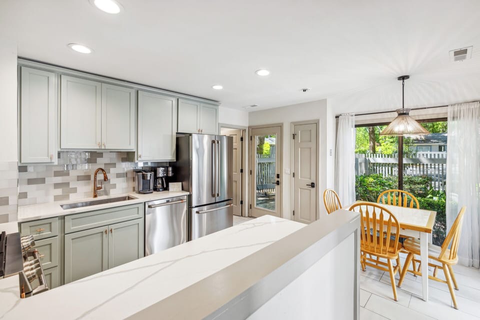 Fully stocked gourmet kitchen with stainless steel appliances, gas stove, Keurig, drip coffee maker and dining area with a courtyard view.