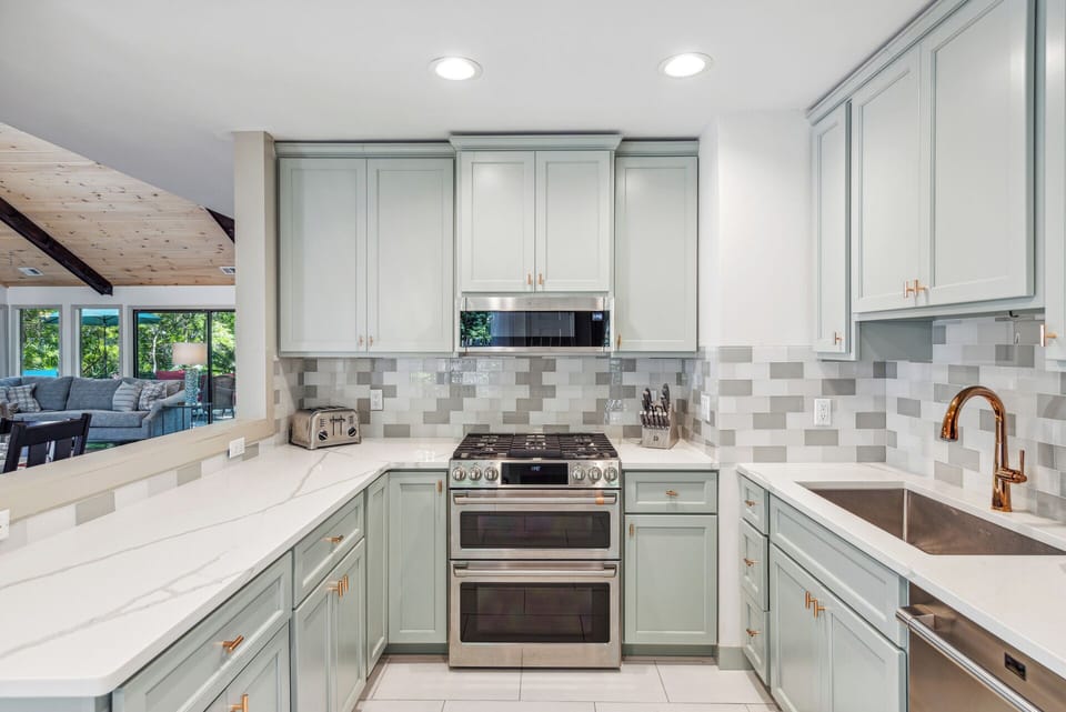 Fully stocked gourmet kitchen with stainless steel appliances, gas stove, Keurig, drip coffee maker and dining area with a courtyard view.