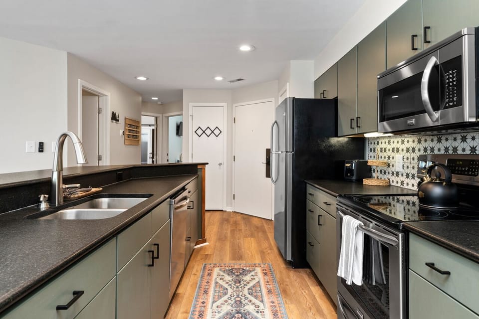 Stainless steel appliances incl. dishwasher, oven, stove, microwave, and fridge.