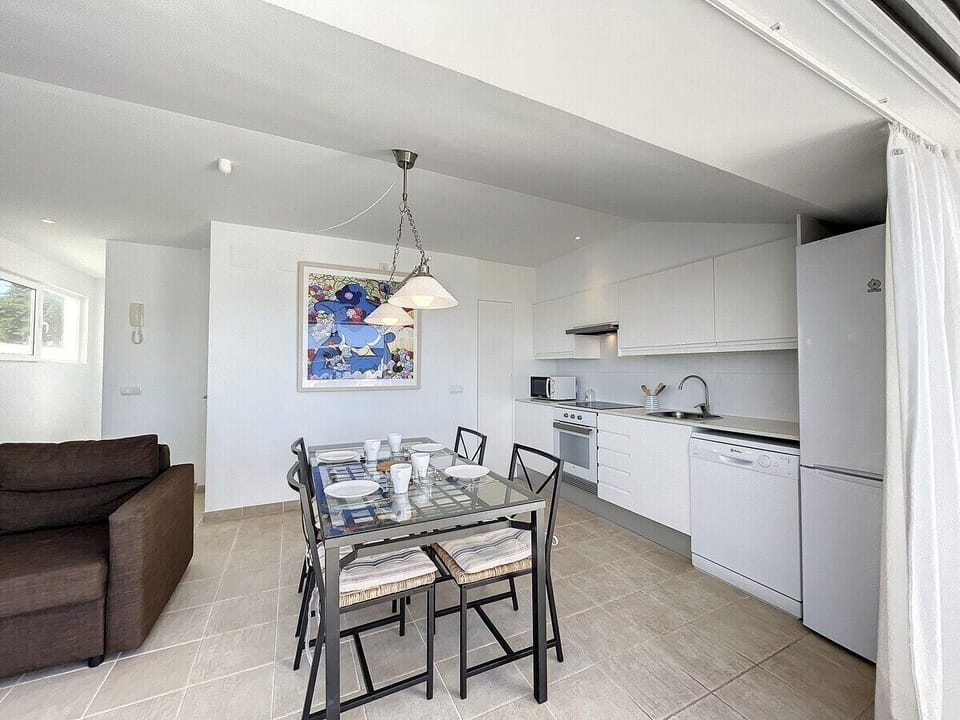 Living and dining room with modern open kitchen, equipped with dishwasher, hob, oven, and Dolce Gusto coffee