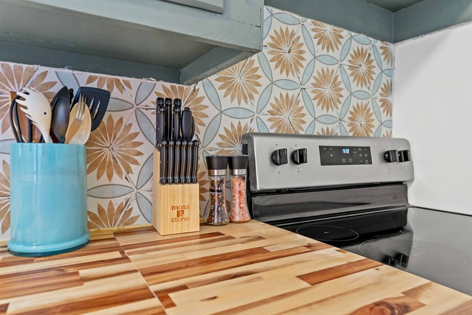 Fully stocked cooking area with coordinated cookware and colorful backsplash details.