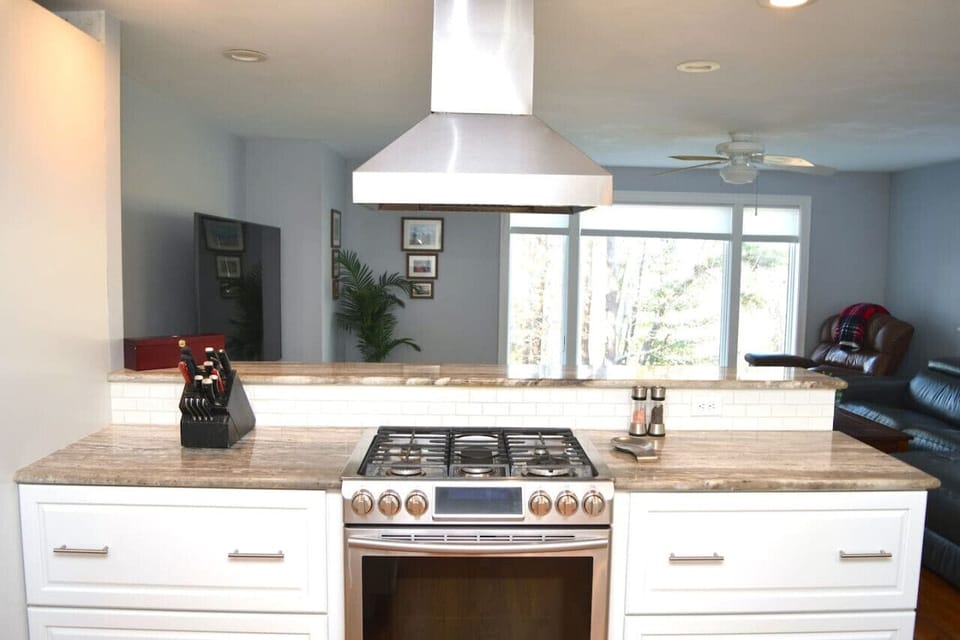Open kitchen design with counter top with seating for 3 overlooking the living room and pond view window