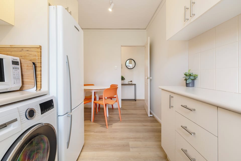 There is a large oven and stovetop with a range hood, microwave and dishwasher. The kitchen also includes additional conveniences such as a Nespresso machine and a washing machine.