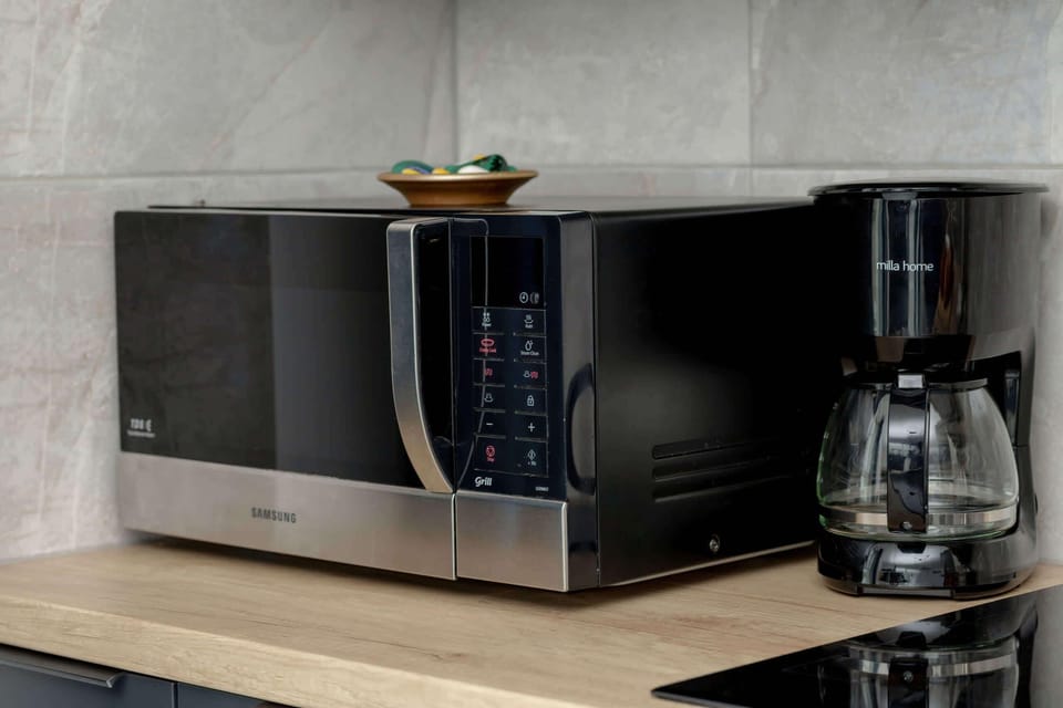 A neatly arranged microwave and coffee machine on a wooden countertop in a sleek, modern kitchen.