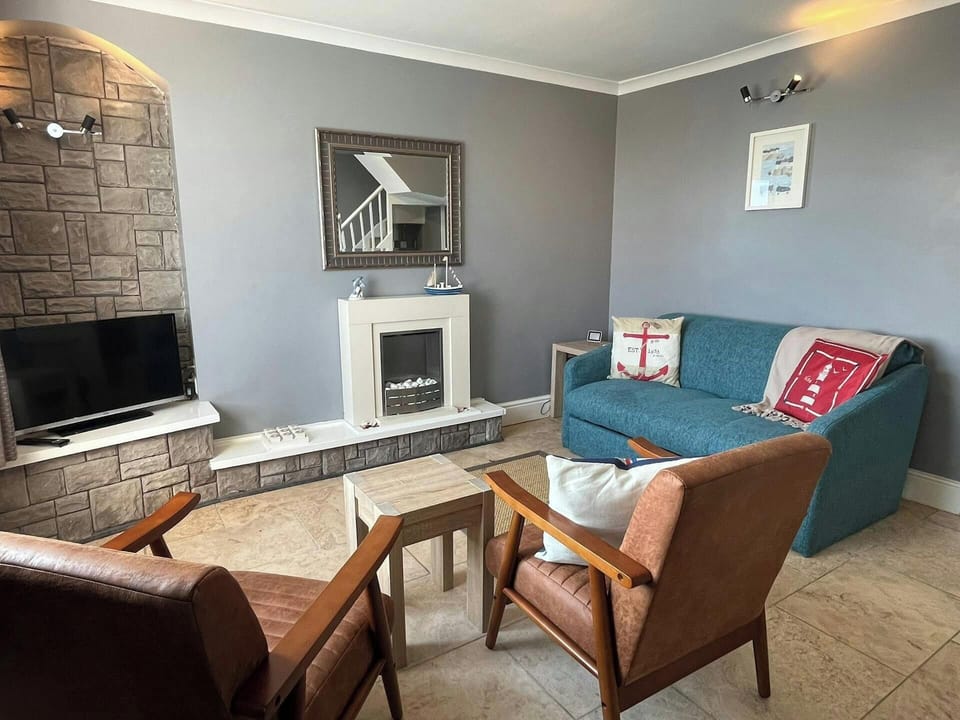 Sitting room with a two seater sofa, 2 armchairs and TV