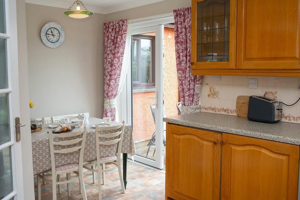 Kitchen cabinets, dining table set for four, patio doors leading to decking area