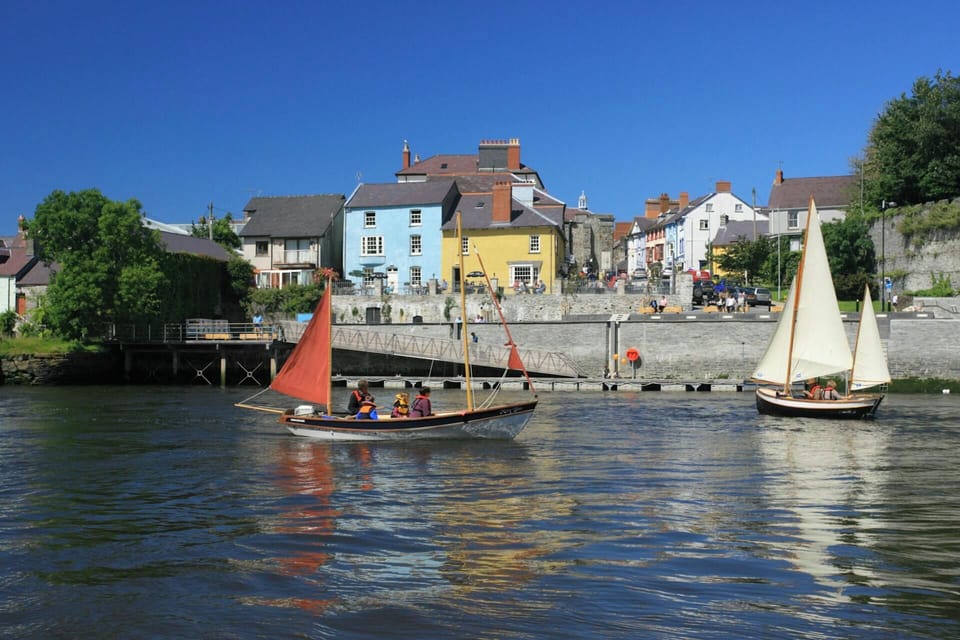 Boats and yachts on the river in Cardigan with shops and restaurants in the background