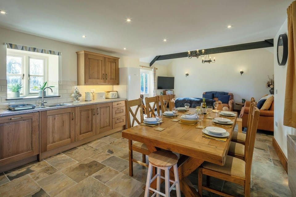 Kitchen cabinets, sink, fridge, table and chairs laid for lunch