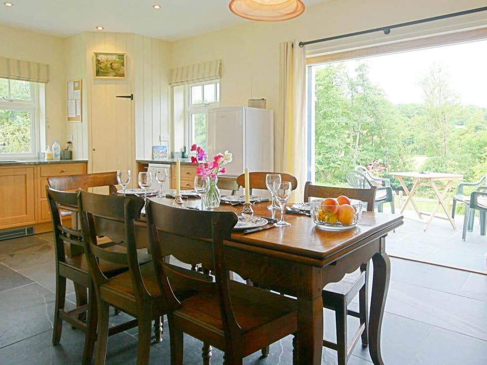 Dining area with table and seven chairs, fridge/freezer and doors leading to the patio with additional table & chairs outside