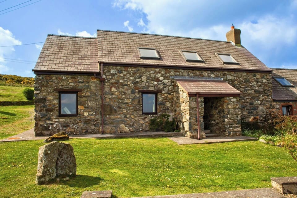 Front of stone house with porch and lawn in foreground