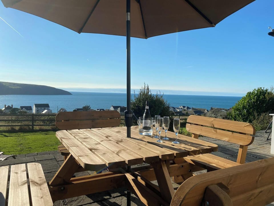 Garden table and benches with a parasol and bottle of wine and glasses