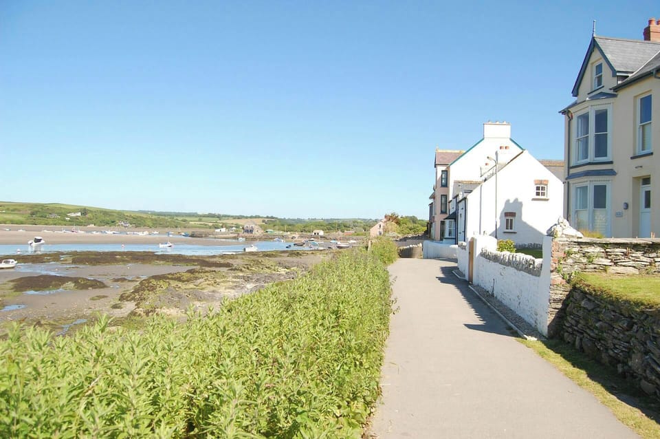 View of coastal path with houses on the right and the sea and estuary to the left