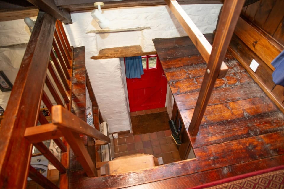 View from bedroom area down wooden steps to ground floor