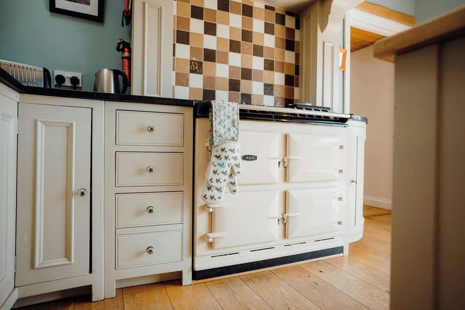 Range cooker in kitchen with cream units, wooden floor and checkered tiles