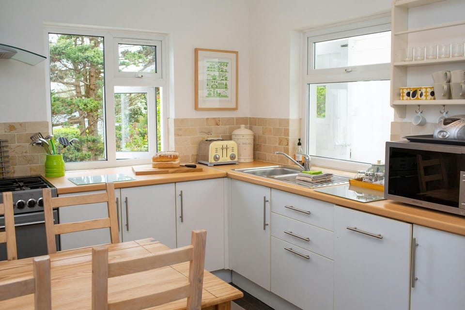 Kitchen with microwave, sink, cooker, toaster, dining table and chairs
