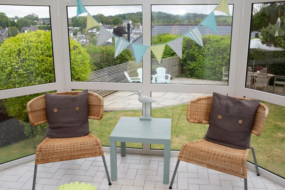 Conservatory with two chairs, coffee table, view of garden and patio