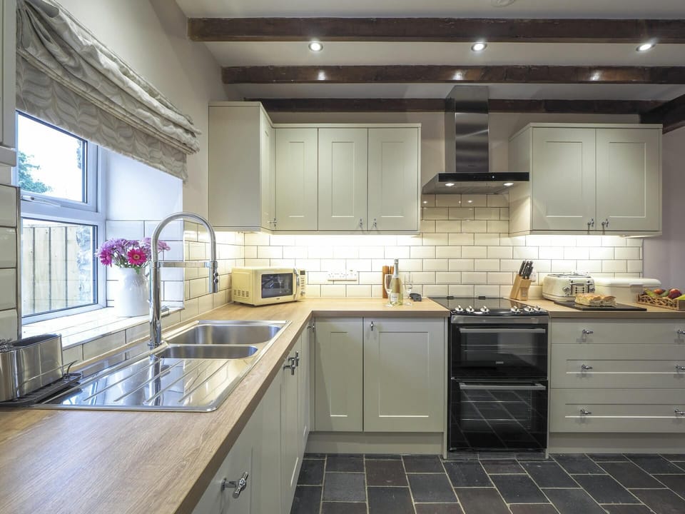 White wall and base units. Microwave. Window with blind looking over the garden