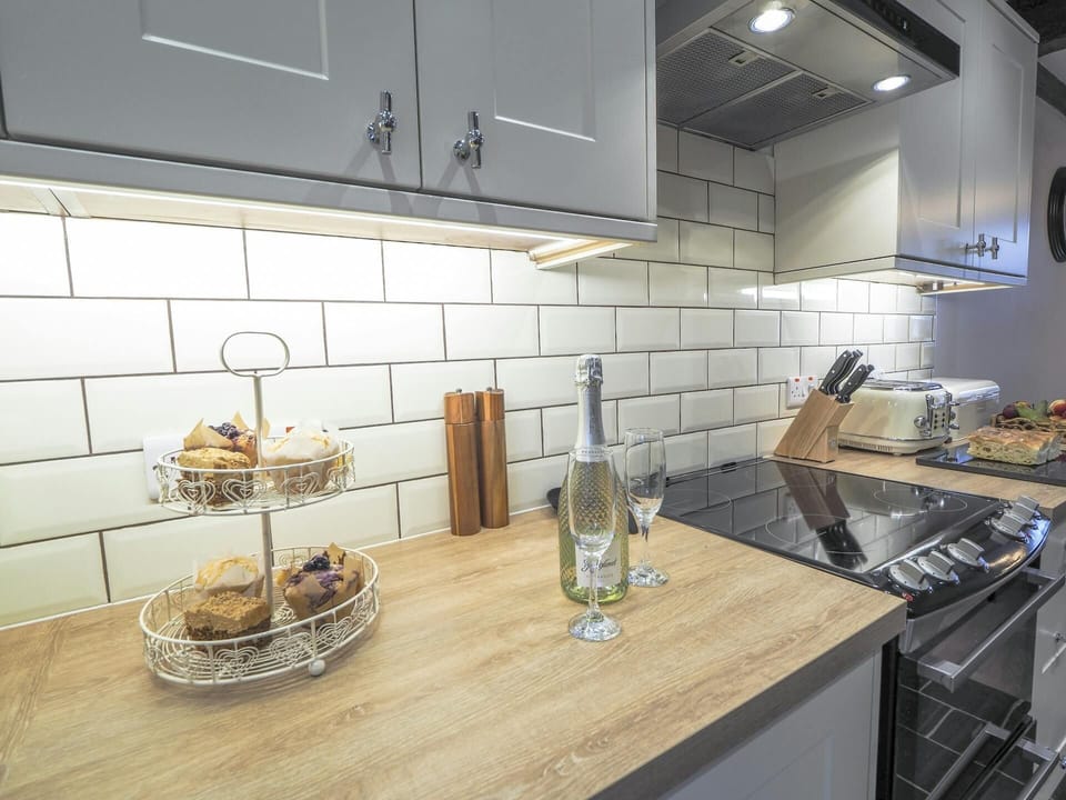 Wooden work surface with a bottle of wine and glasses. Electric cooker