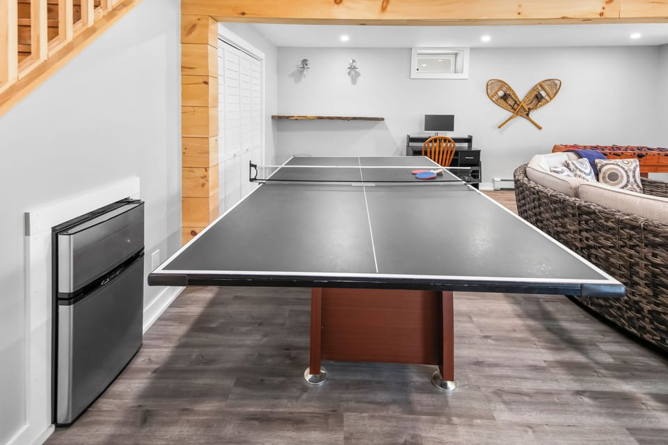 Fun lower-level game room with ping pong table, cozy lounge seating, and work desk