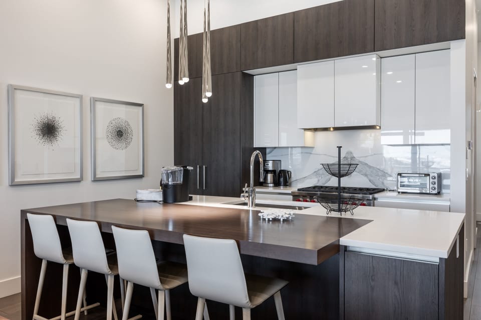 - Modern kitchen with sleek cabinetry and waterfall island design  
- High-end appliances including oven, stove, and coffee maker  
- Open concept perfect for cooking and gathering after skiing