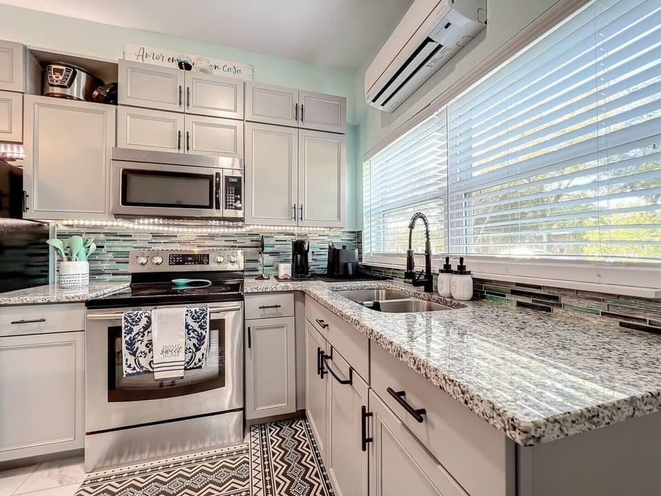 This kitchen includes functional cabinets for ample storage, a stove with an oven, and a microwave, providing all the essentials for cooking and heating meals.