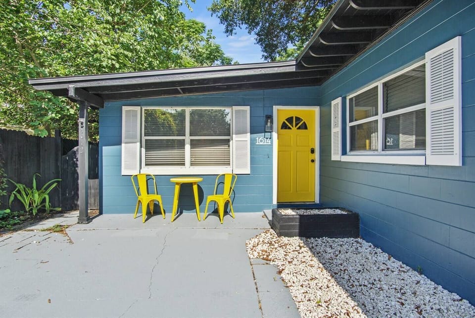 Charming entrance with a bright yellow door and outdoor seating.