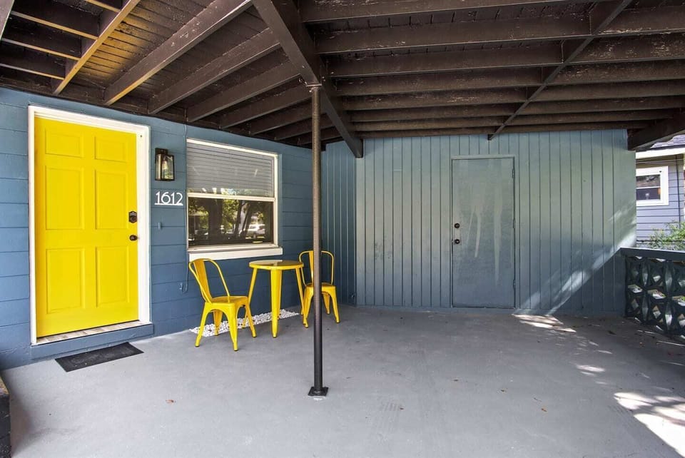 Charming entrance with a bright yellow door and outdoor seating.