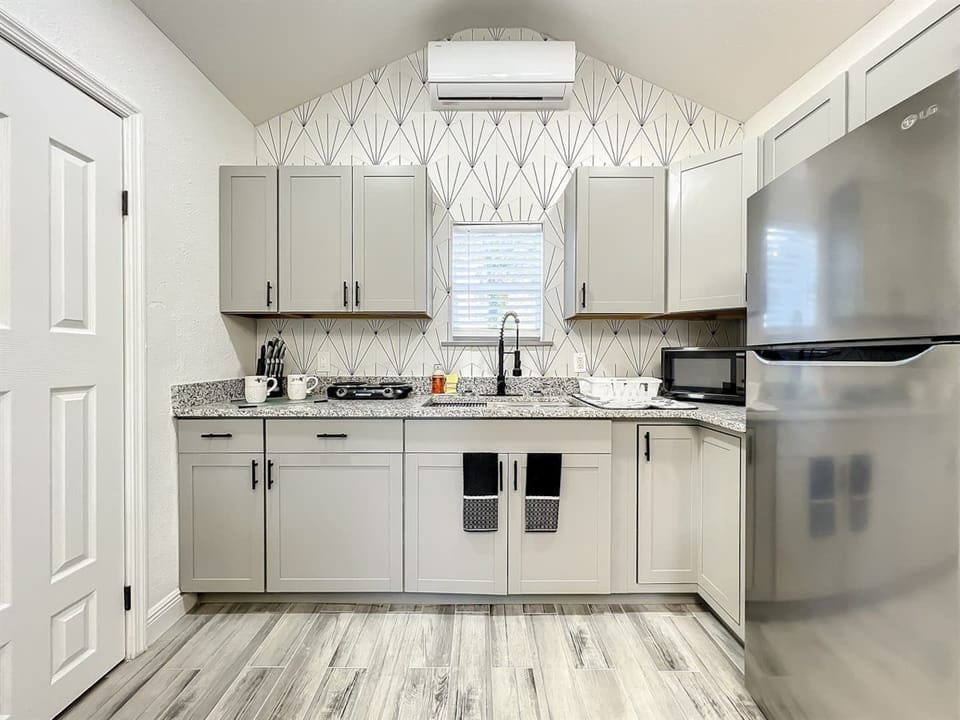 Kitchen with cabinets, a small two-burner stove, microwave, and refrigerator