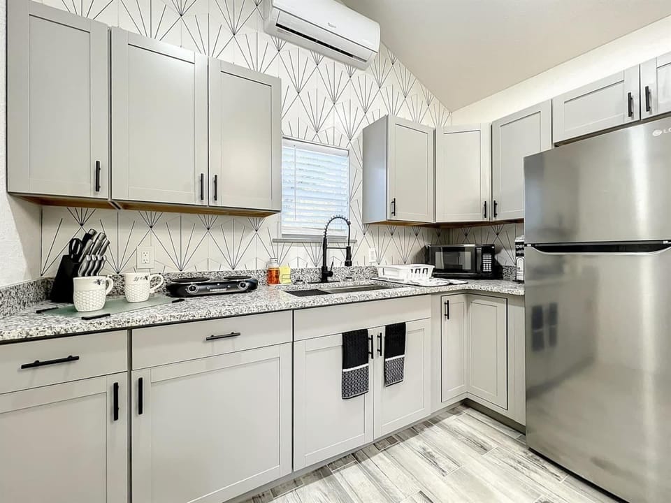 Kitchen with cabinets, a small two-burner stove, microwave, and refrigerator