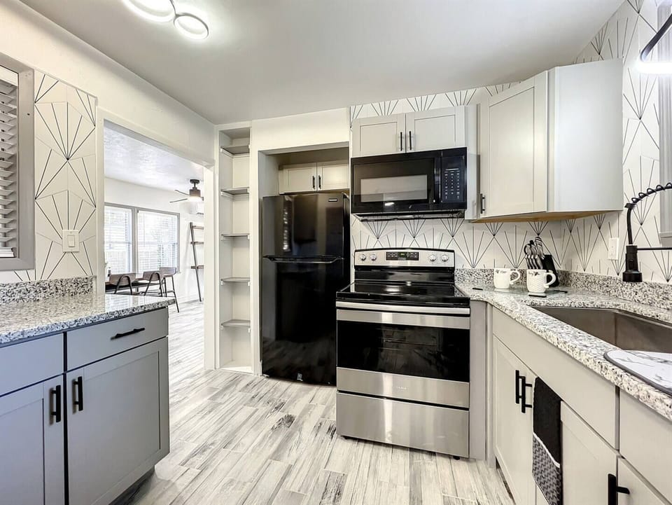 Kitchen with four-burner stove, oven, cabinets, refrigerator and microwave oven