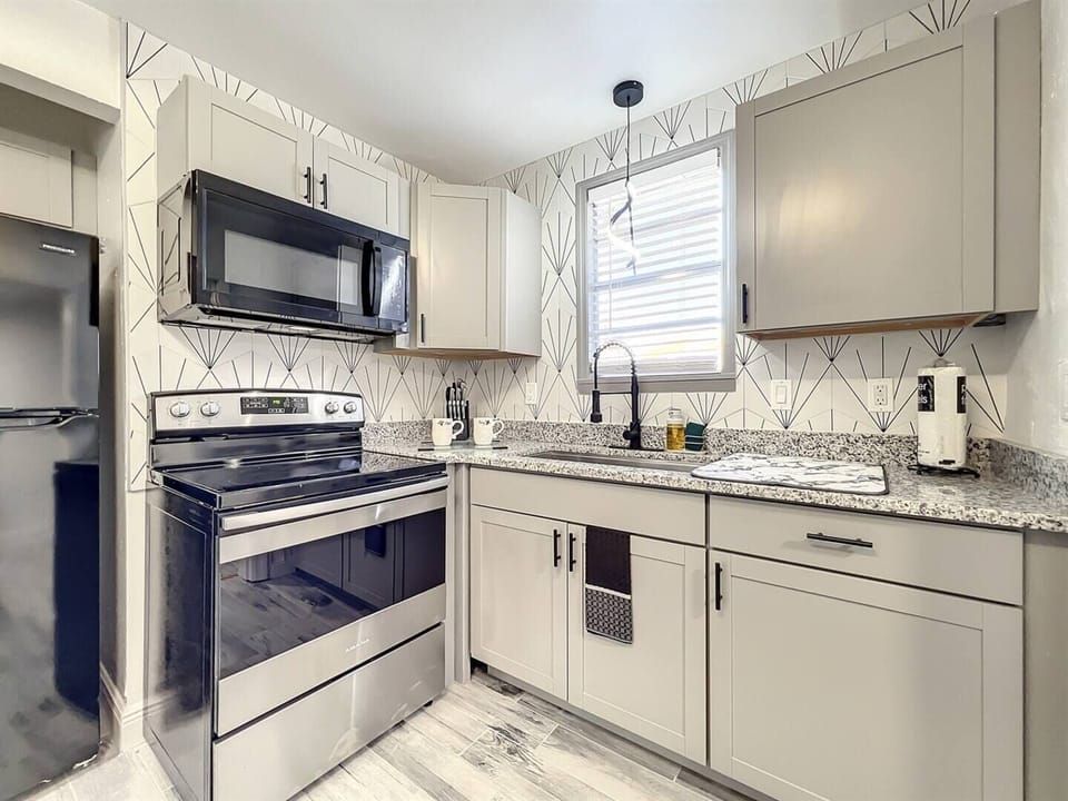 Kitchen with a four-burner stove, oven, cabinets, and microwave