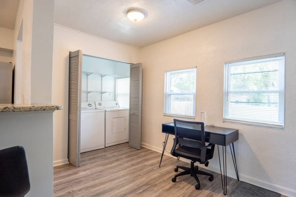 A desk and laundry area are located close to each other, creating a practical and multifunctional space.