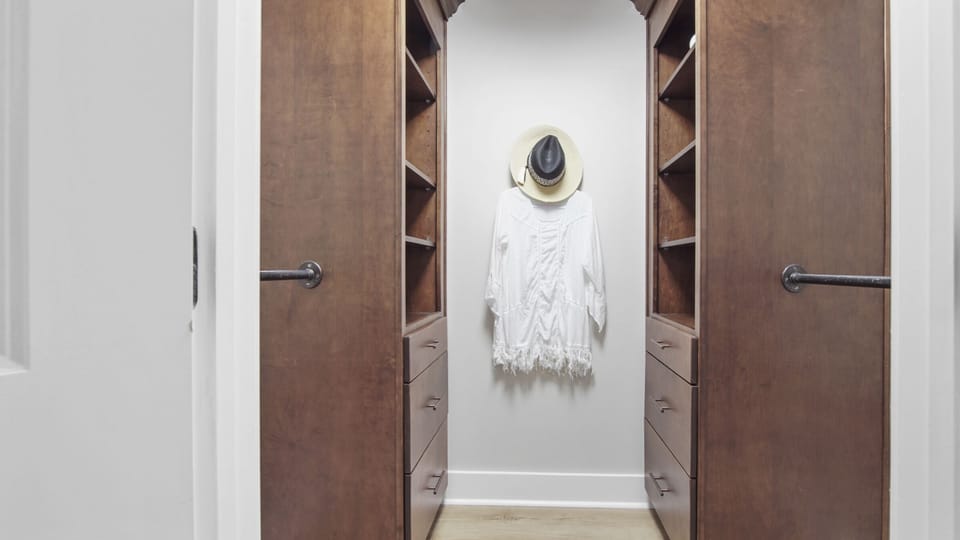 Guest walk-in closet with custom closet cabinetry.