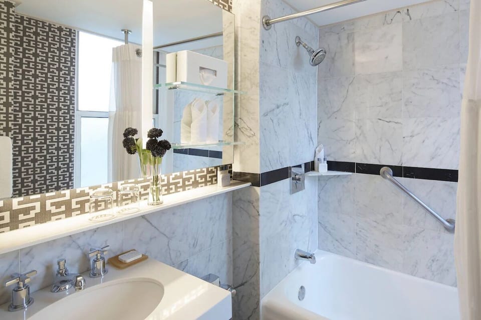 Soak and reset in a sleek marble bath-shower combo.