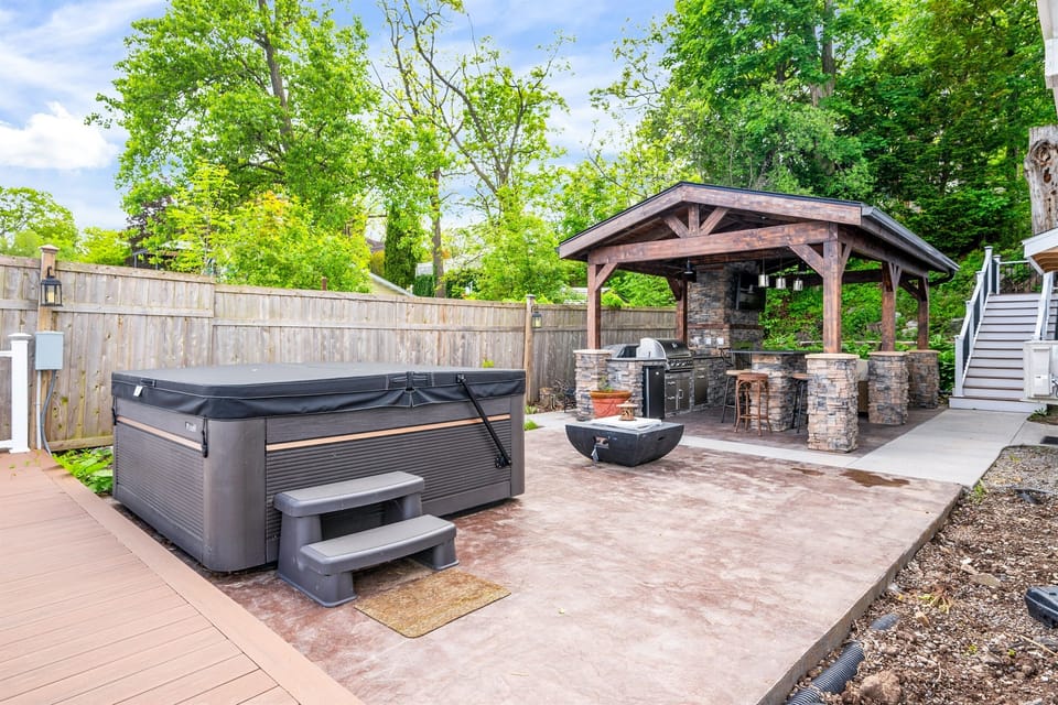 Entertain in style with a covered stone kitchen, grill, hot tub, and fire feature—your backyard retreat 🍔🔥🍷