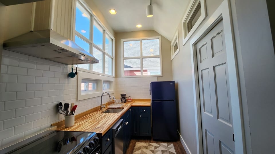 Kitchen equipped with an oven, dishwasher, fridge, and basic cooking utensils.