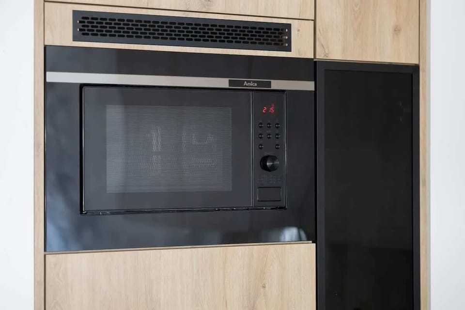 A close-up view of a black microwave built into a wooden kitchen unit. A compact and efficient kitchen appliance solution.