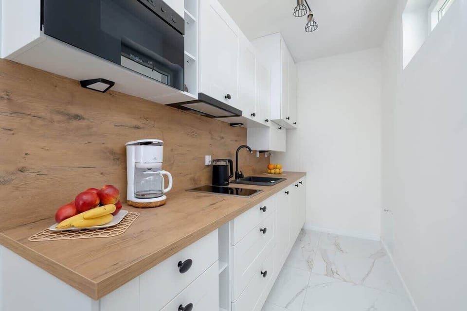 A close-up of a kitchen countertop featuring a wooden surface, with a kettle and other kitchen essentials, showing the apartment’s modern yet functional kitchen design.