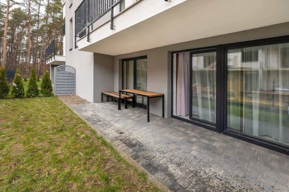 The outdoor area features a small patio space with seating, accessible from the apartment. There is a green lawn, making it a nice place to relax outside.
