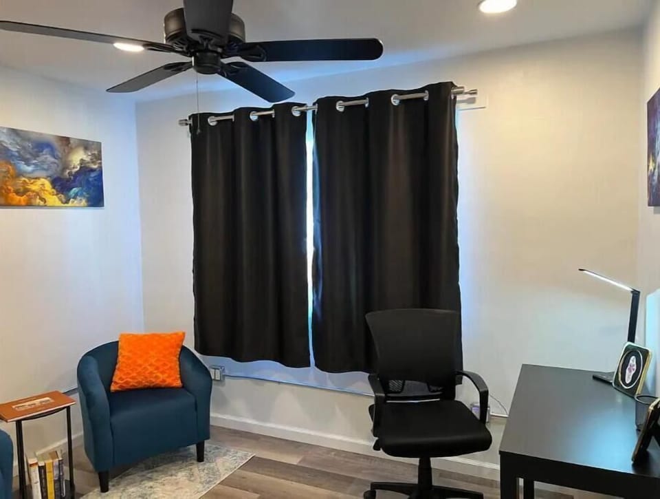 Work space with desk, chair, lamp, & reading area with chairs & books.